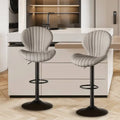 Two sleek light gray upholstered bar stools with vertical stitching and black metal bases for luxury women’s fashion seating