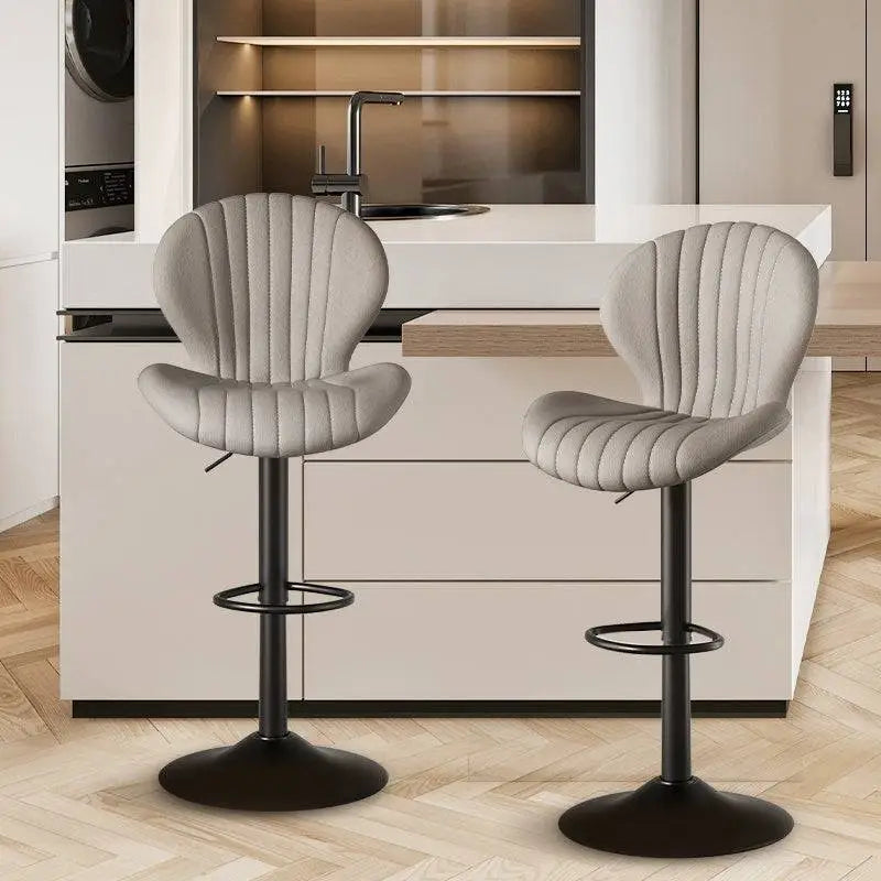 Two sleek light gray upholstered bar stools with vertical stitching and black metal bases for luxury women’s fashion seating