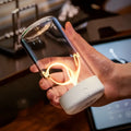A sleek rechargeable portable night light led camping light with a transparent glass cylinder and white base