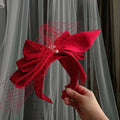 A vibrant red satin wedding satin headband featuring a bow fashion bridal design with mesh and central pearl embellishment