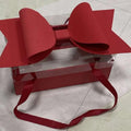 A vibrant red bow knot adorns a clear window handheld flower box with matching red fabric handles
