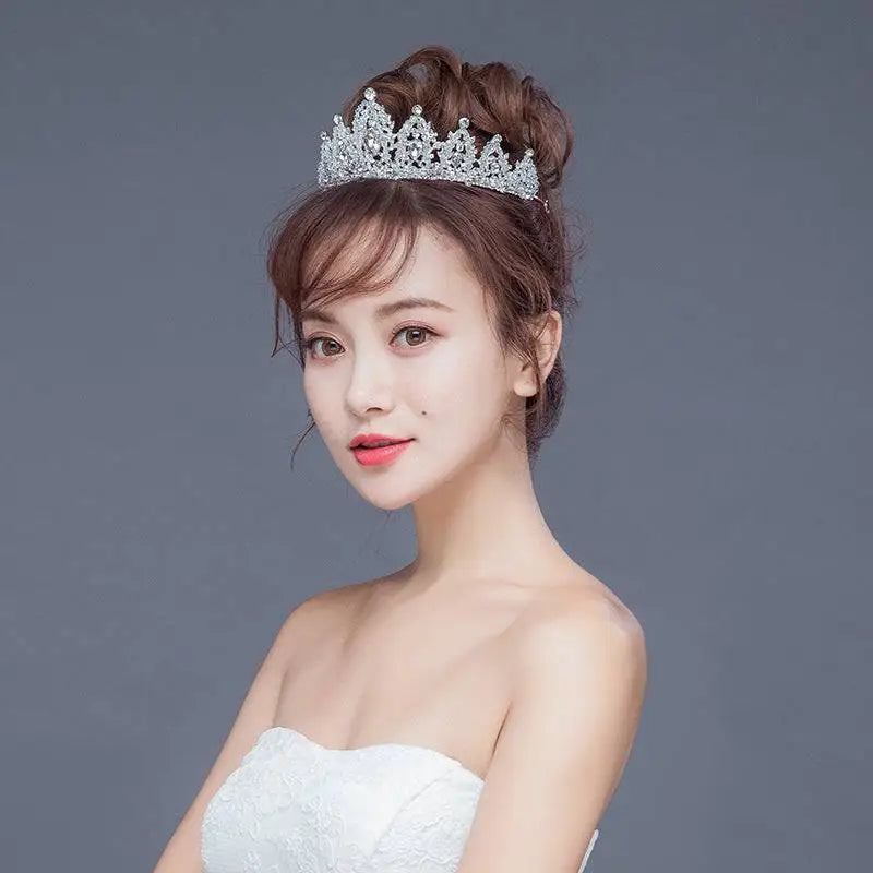 A sparkling silver crystal alloy crown wedding accessory with intricate details and a regal pointed design