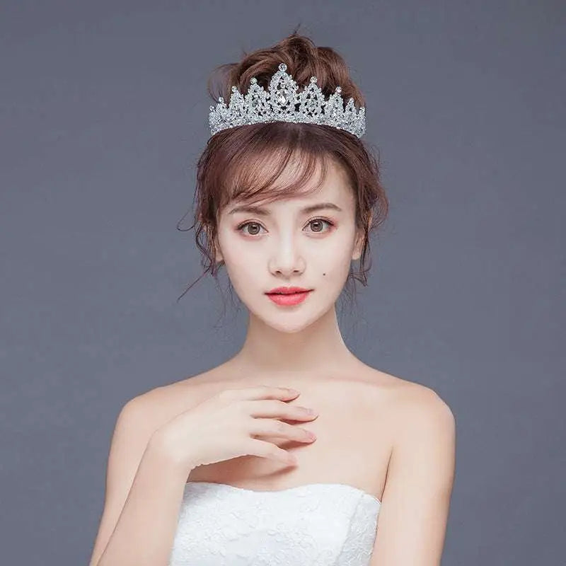 A sparkling silver crystal alloy crown wedding accessory with intricate details and a regal pointed crown design
