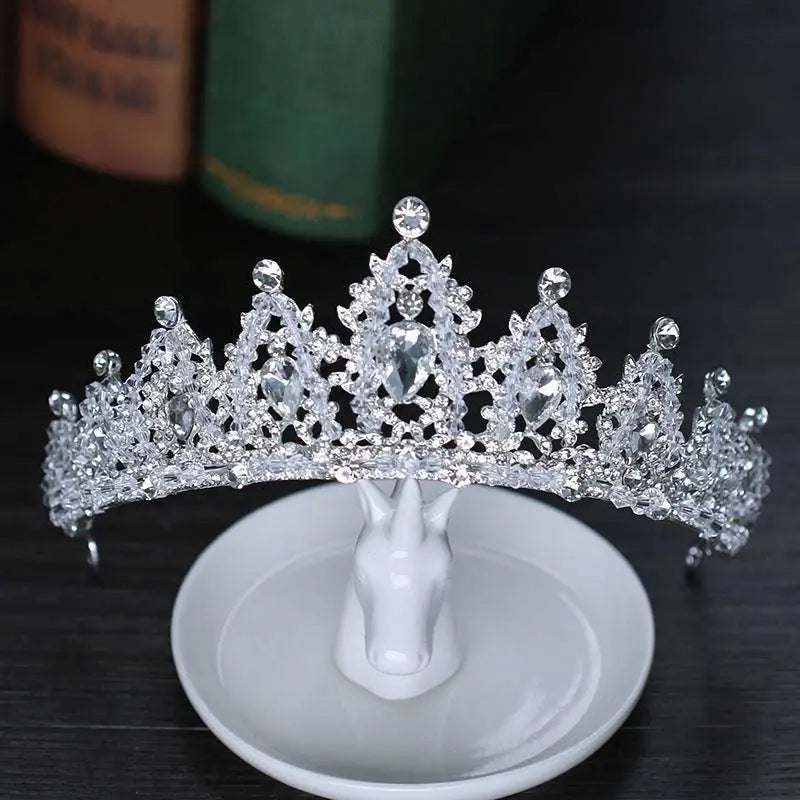 A sparkling silver crystal alloy crown wedding accessory with intricate embellishments and a central teardrop gemstone