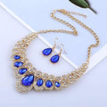 A glamorous red crystal teardrop american jewelry fashion set with gold tones, royal blue crystals, and matching earrings