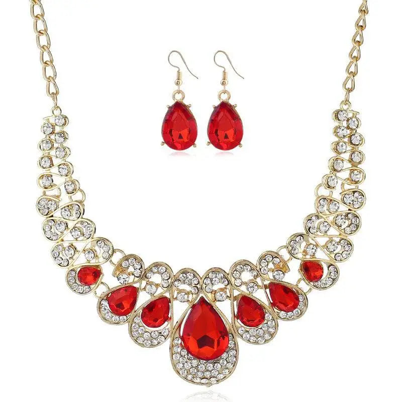 Gold-toned necklace featuring a bold red crystal teardrop centerpiece with clear crystals and intricate metalwork american jewelry fashion