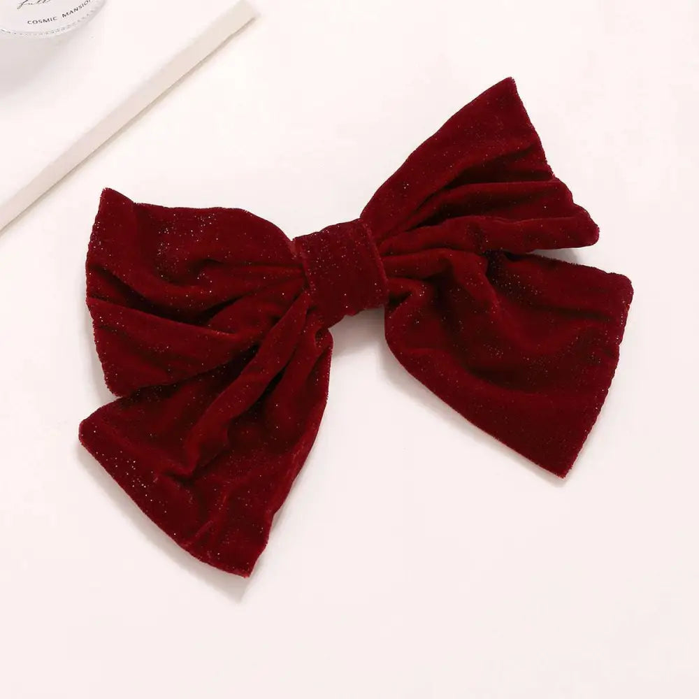 A plush deep red velvet red flannel big bow spring clip accessory with a subtle glittery finish for spring styling