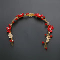 A delicate red floral costume jewelry set headpiece with gold-toned leaves and sparkling crystals for weddings