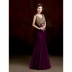 A woman wears an elegant deep purple red gold beaded fish tail banquet evening dress with intricate gold embroidery