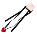 A red heart pendant on a black sash necklace with a pink ellison young brand tag highlights the red black sash design