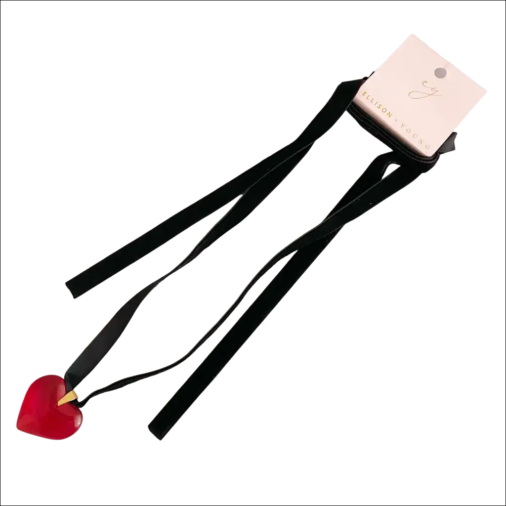 A red heart pendant on a black sash necklace with a pink ellison young brand tag highlights the red black sash design