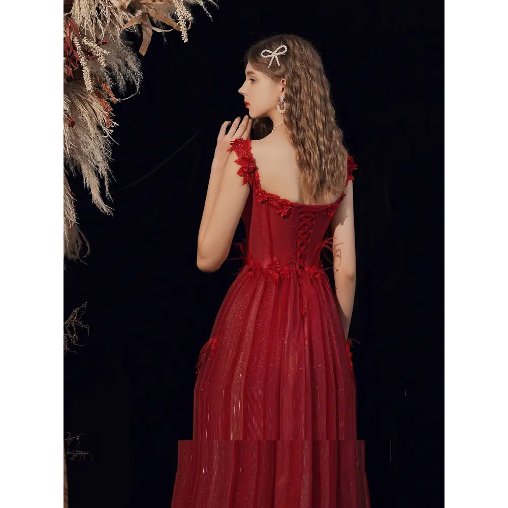 A woman wears a red lace off shoulder wedding toast dress with lace-up detailing and layered tulle skirt