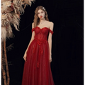 A vibrant red lace off shoulder wedding toast dress with intricate shimmering red lace and a flowing tulle skirt