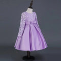 A lavender long sleeve satin princess dress with red lace floral embroidery and a flared skirt cinched by a matching bow