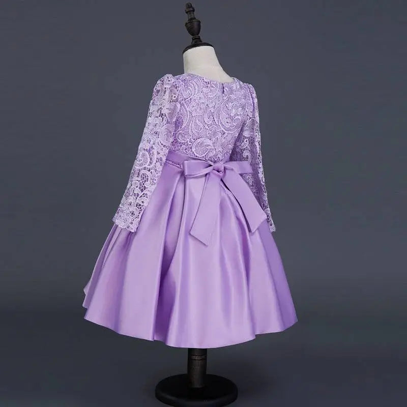 A lavender lace princess dress long sleeve satin skirt with fitted bodice and matching satin bow at the waist