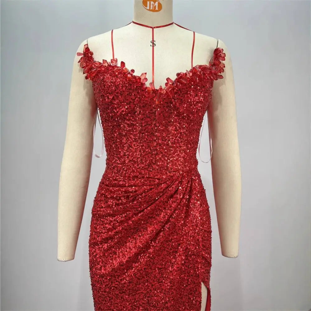 A dazzling red shimmering red paillette tube high slit gown with floral shoulder embellishments and side slit