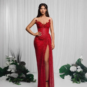 A shimmering red paillette tube high slit sequin gown with floral embellishments and a high slit detail