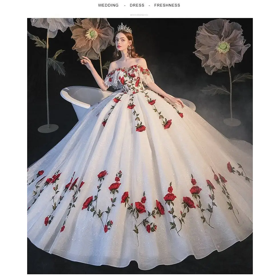 A white off-the-shoulder wedding gown with red rose embroidery and temperament bride bra trailing on a voluminous tulle skirt