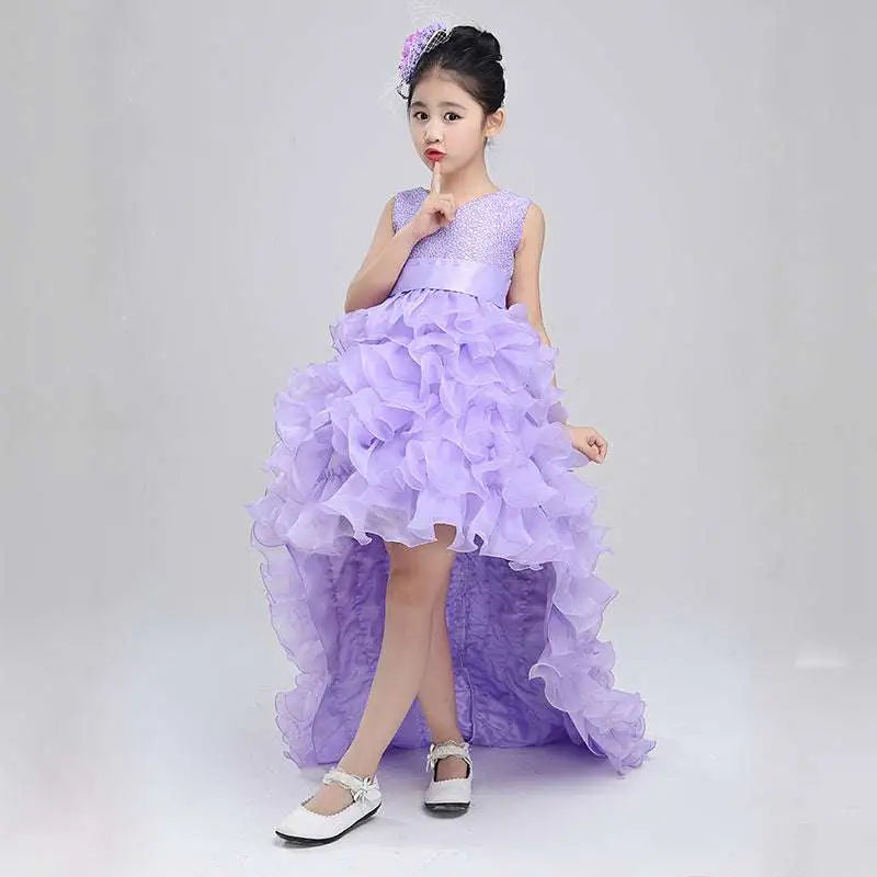 A young girl wears a lavender ruffled girls dress wedding gown with a sparkling bodice and matching floral headpiece