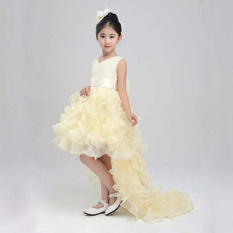 Ivory lace wedding flower girl dress with fitted bodice and voluminous ruffled skirt with asymmetrical train
