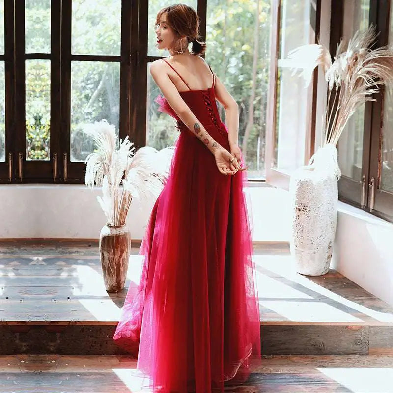 A flowing red satin engagement suspender evening dress with thin spaghetti straps and a fitted bodice