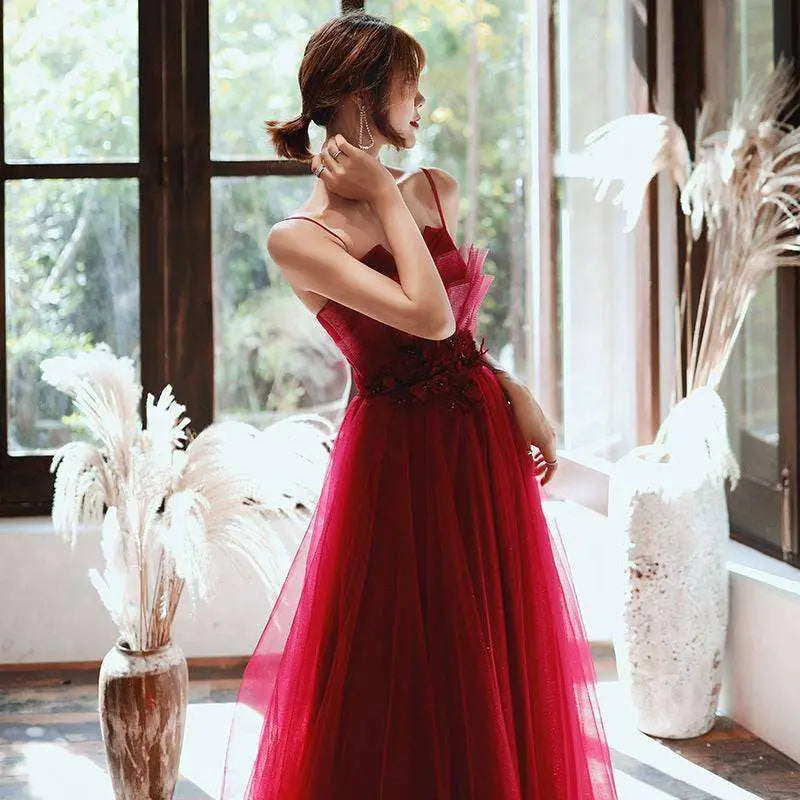 A red satin engagement suspender evening dress featuring a flowing tulle gown with a fitted floral bodice and thin straps