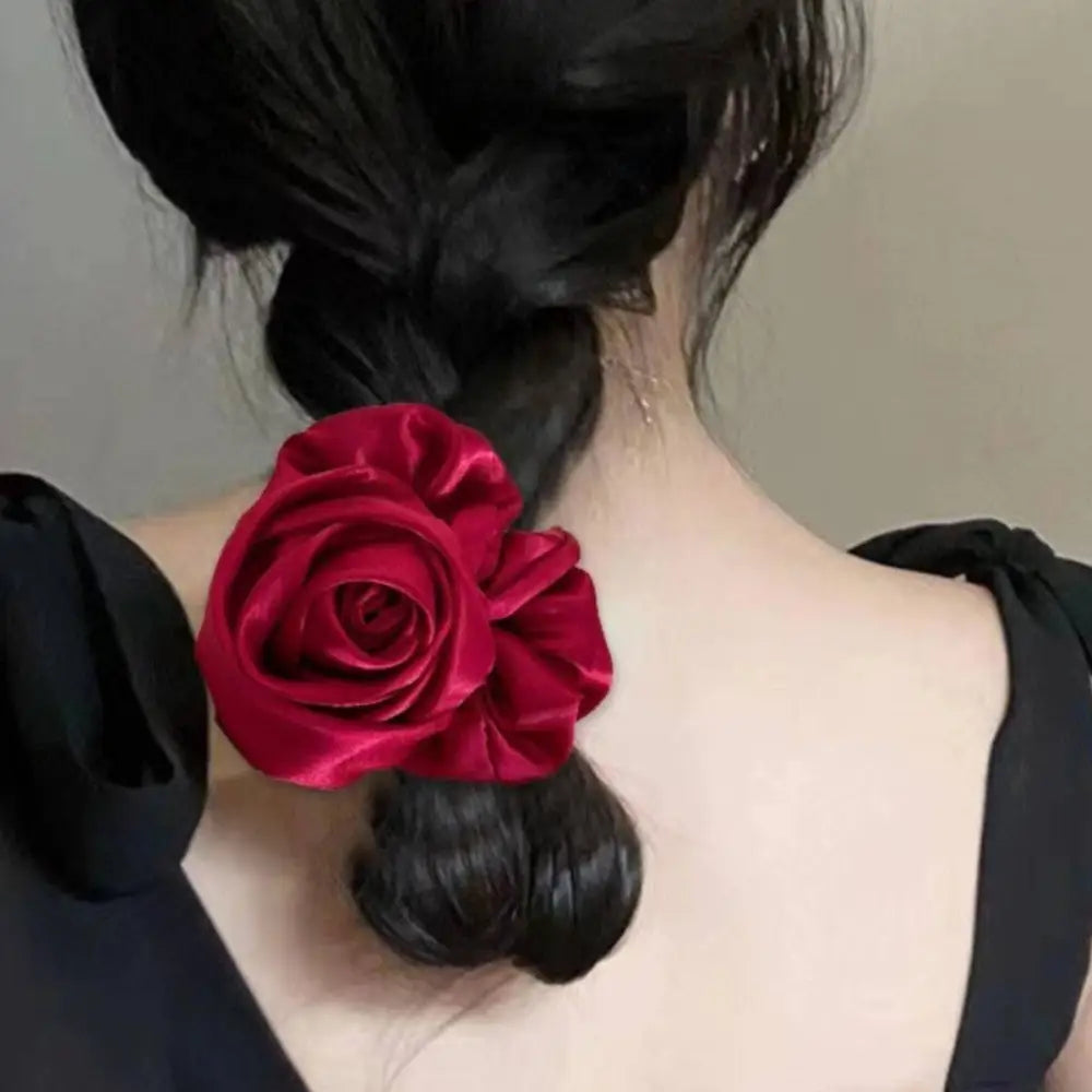 A vibrant red satin rose hair band adorning a black braided bun ponytail advanced for elegant styling with advanced sense