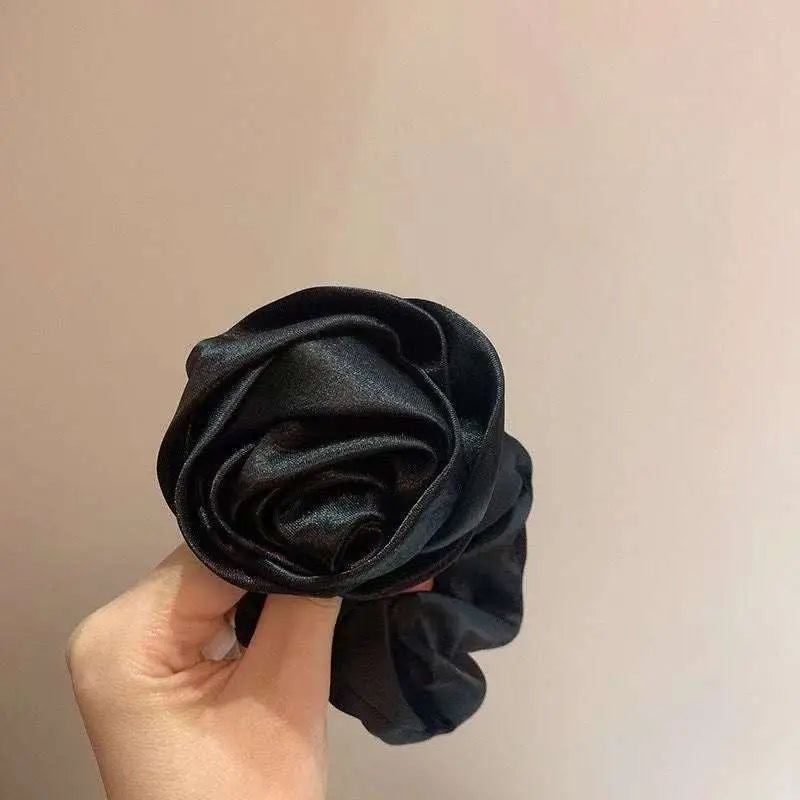 A vibrant red satin rose hair band adorning a black braided bun ponytail advanced for elegant styling with advanced sense