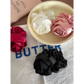 Three satin rose hair band scrunchies in white pink and black on a cream plate for bun ponytail advanced sense styling