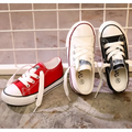 Three classic low-top canvas casual shoes student style in red toddler, white, and black with matching rubber soles