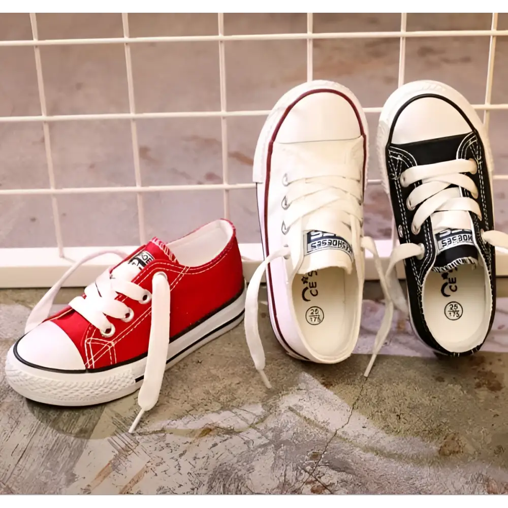 Three classic low-top canvas casual shoes student style in red toddler, white, and black with matching rubber soles