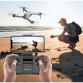 Gray folding drone with four propellers hovering above a sandy beach featuring mobile phone control and gps positioning