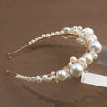 A retro bridal headdress featuring a gold-toned simple pearl headband with an elegant cluster of white pearls