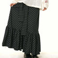 A black and gray checkered fishtail skirt with a matching ruffled plaid design and a belt tied at the waist