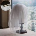A delicate white retro short wedding lace floral veil with metallic clasp displayed on a mannequin head