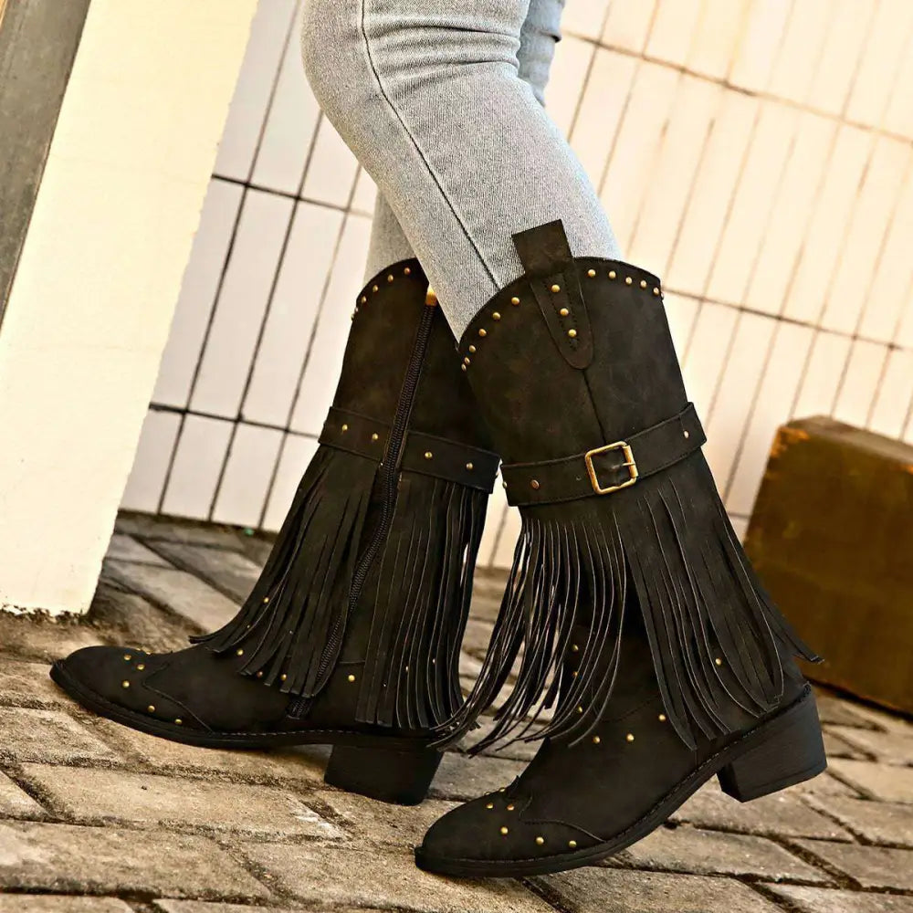 Black suede cowboy boots with gold-tone studs and fringe detailing for retro winter fashion style