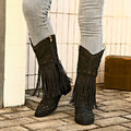 Black suede cowboy boots with gold-tone studs and fringe detailing for retro winter fashion style