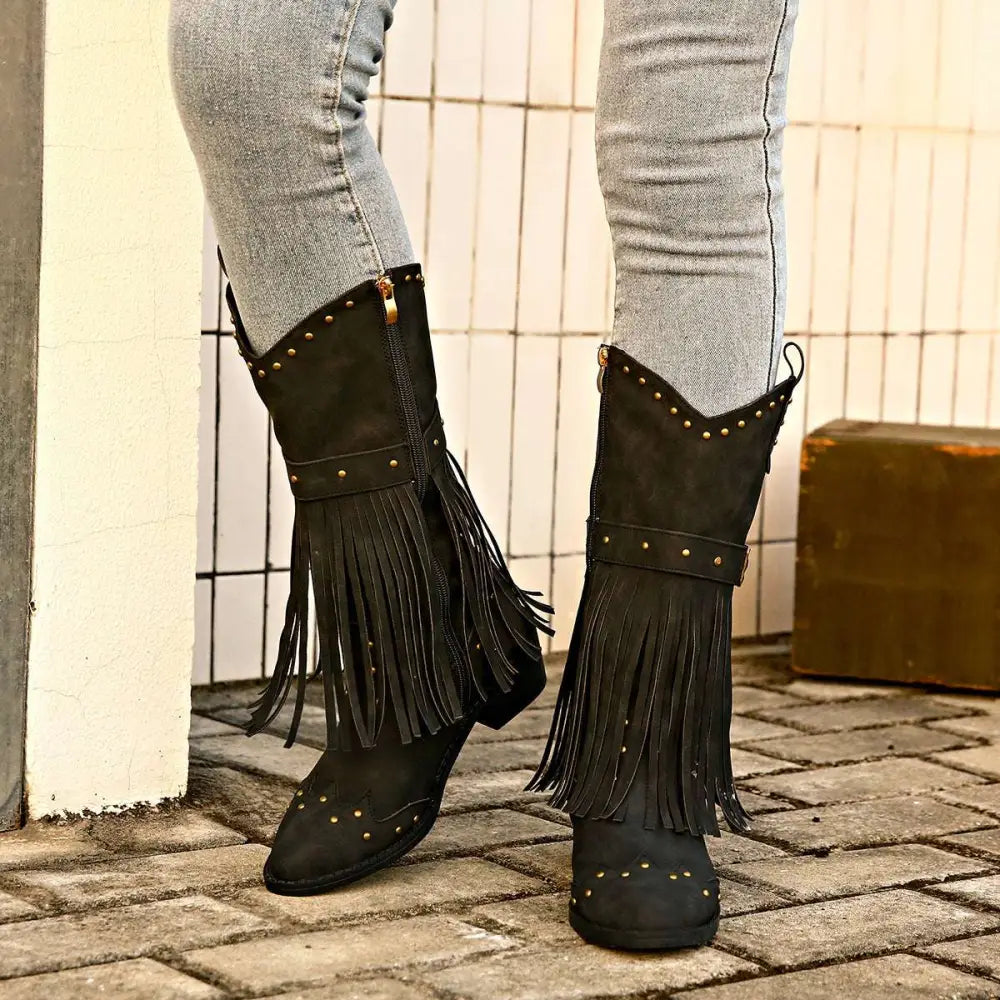 Black suede cowboy boots with gold-tone studs and fringe detailing for retro winter fashion style