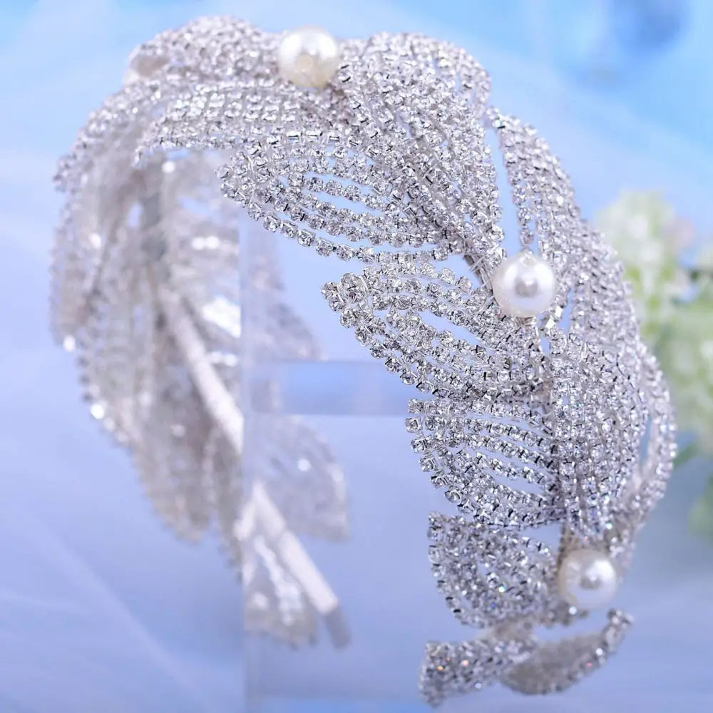 A silver rhinestone leaf handmade headband with clear rhinestones and three white pearls for bridal wear