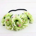 A delicate blue floral rose headband with soft green and pink artificial roses and a black elastic band rose color package