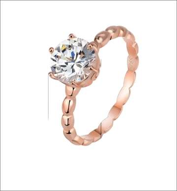 Rose gold beaded sterling silver ring with a round-cut clear gemstone set in four prongs and ornate band