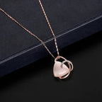 A delicate rose gold heart necklace with a pink triangular pendant surrounded by a diamond accented band