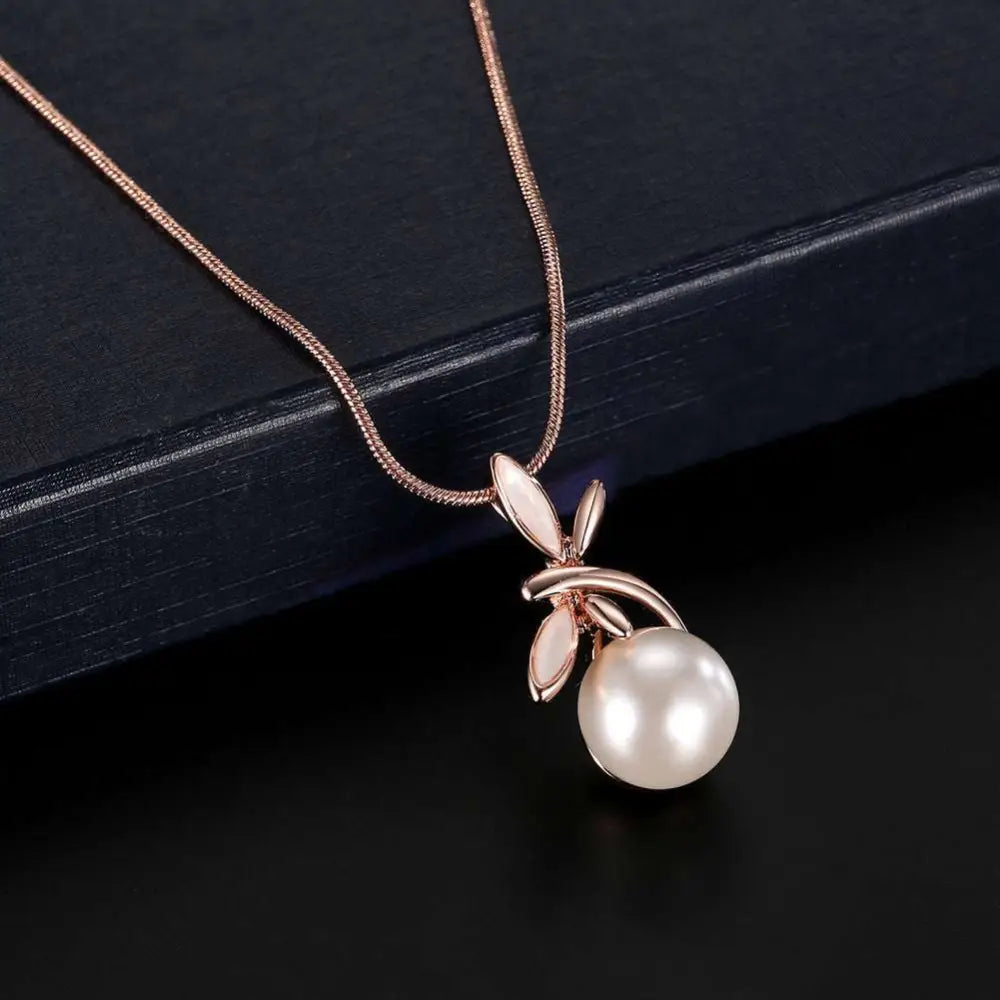 A rose gold pearl necklace earrings bridal set featuring a delicate necklace with a white pearl and leaf charms