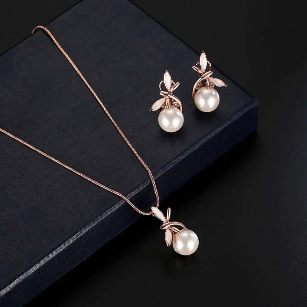 Rose gold pearl necklace earrings bridal set with delicate leaf designs cradling round white pearls