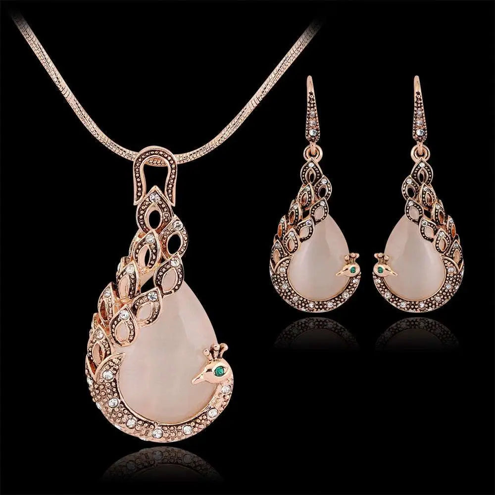 Rose gold peacock jewelry set with translucent pink jade stones and clear crystals featuring intricate metalwork