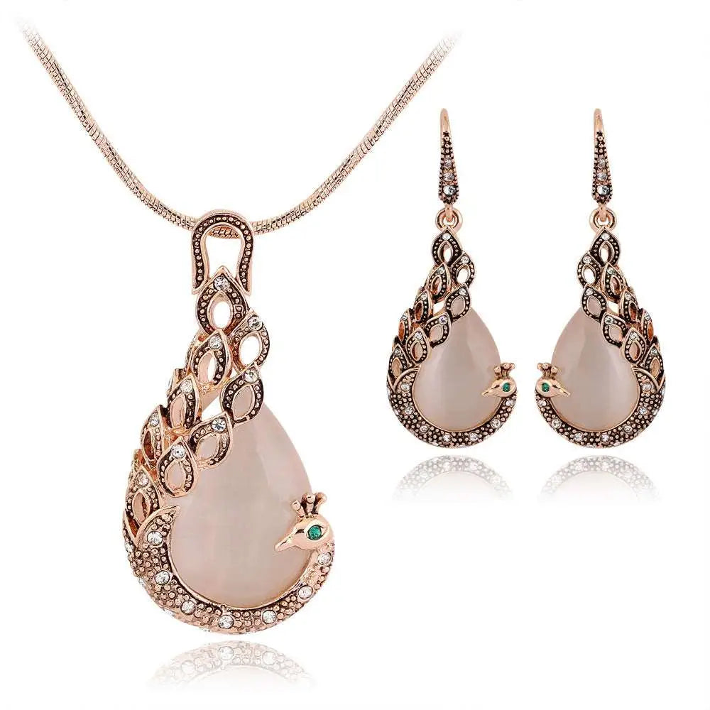 Elegant rose gold peacock jewelry set with pink jade stones, crystal feather detailing, and green gemstone accents