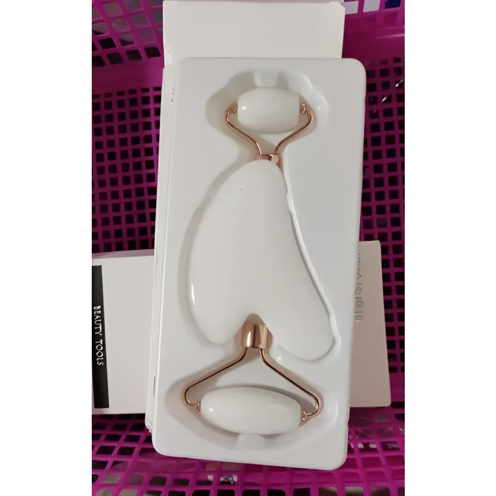 Rose quartz facial roller and gua sha wrinkle remover set with white jade stones and rose gold metal handles in white packaging