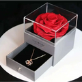A vibrant red preserved rose in a clear acrylic box on a silver gift drawer for royal blue preserved rose jewelry gift