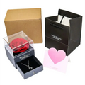 A vibrant red preserved rose encased in a clear acrylic box with a sleek black base for royal blue preserved rose jewelry gift