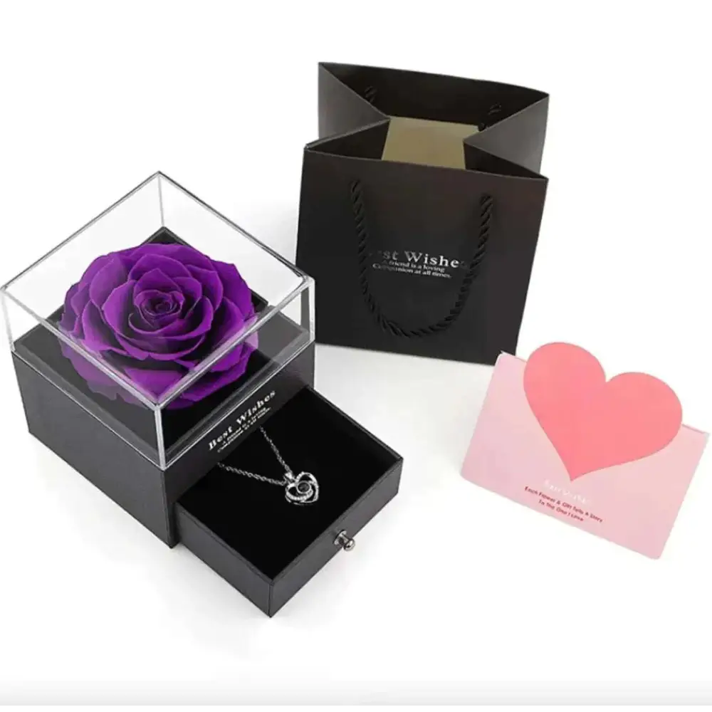 A vibrant purple preserved rose in a clear acrylic cube atop a royal blue preserved rose jewelry gift box